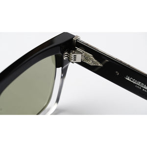 Close-up of a pair of sunglasses showing the black acetate frame, silver metal hinge with a wing emblem, and the black temple arm printed with 'JACQUES M.' on a white background.