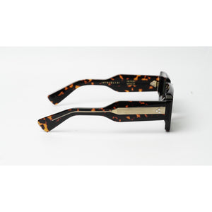 Tortoiseshell acetate sunglasses with a black and brown pattern, featuring a gold metal bridge and silver rhinestone accents, shown from a side profile on a white background.