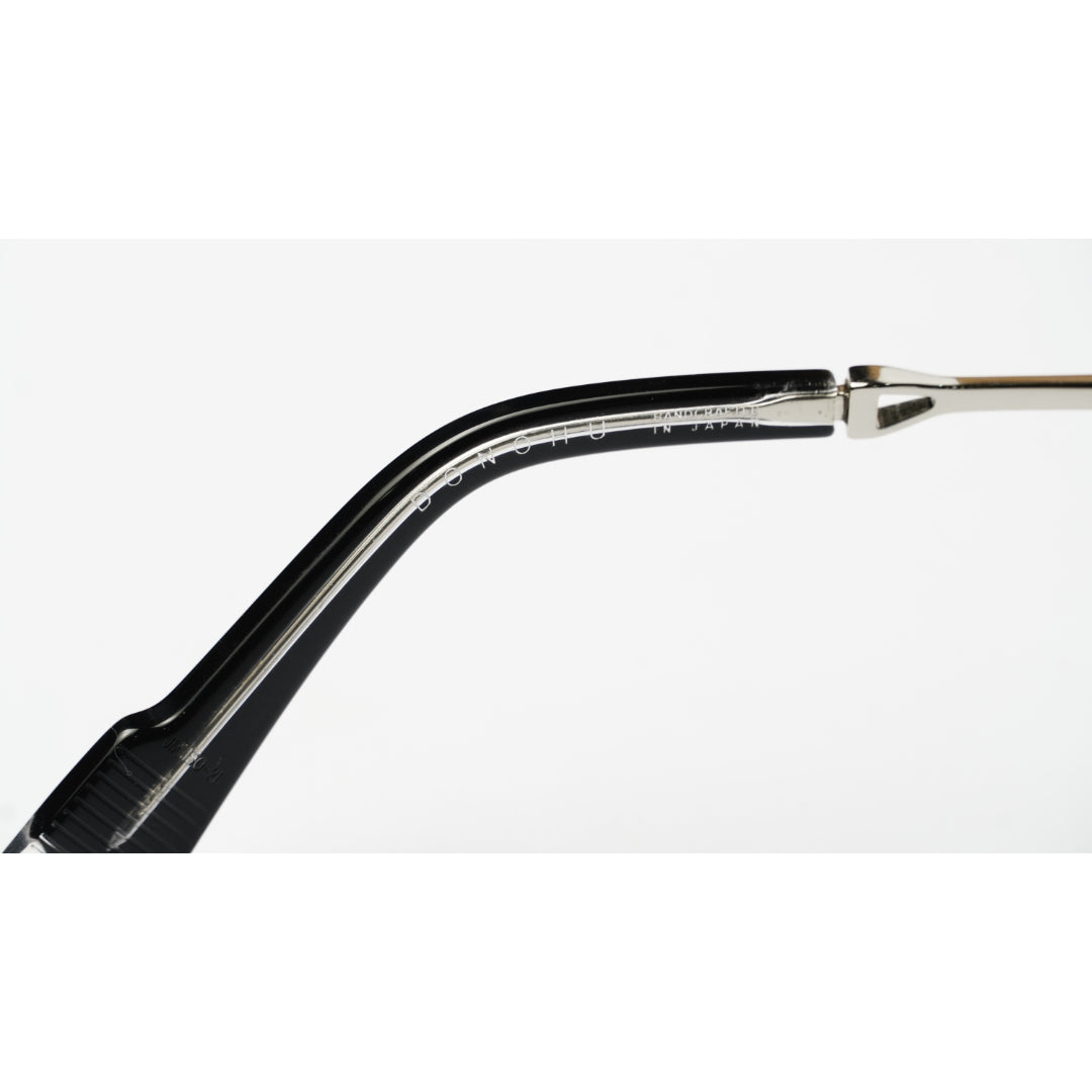 Close-up of a black acetate eyeglass frame arm with a silver metal hinge on a white background.