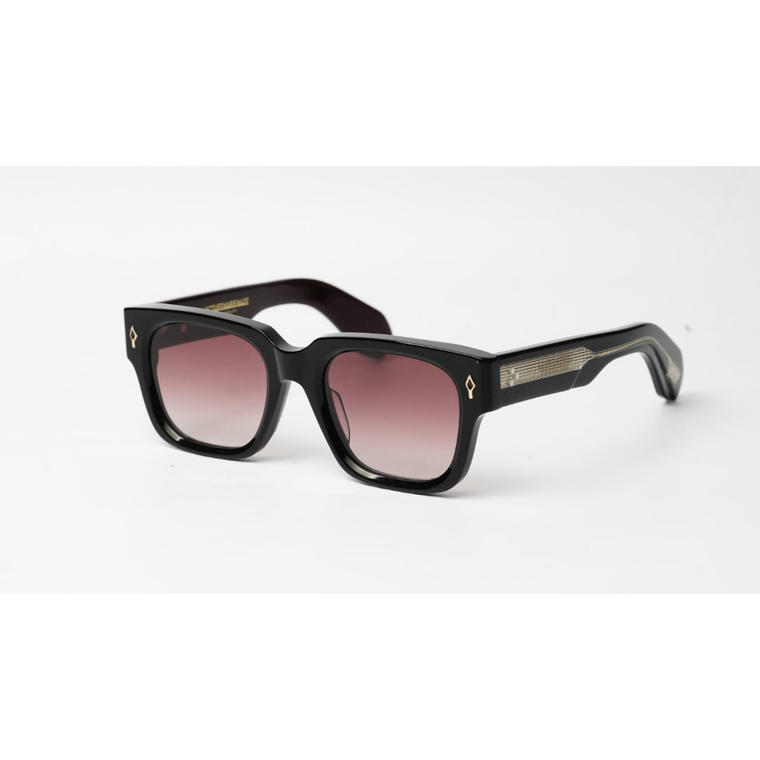 Black square sunglasses with gradient pink-tinted lenses and small gold geometric logo details on the temples, shown on a white background.