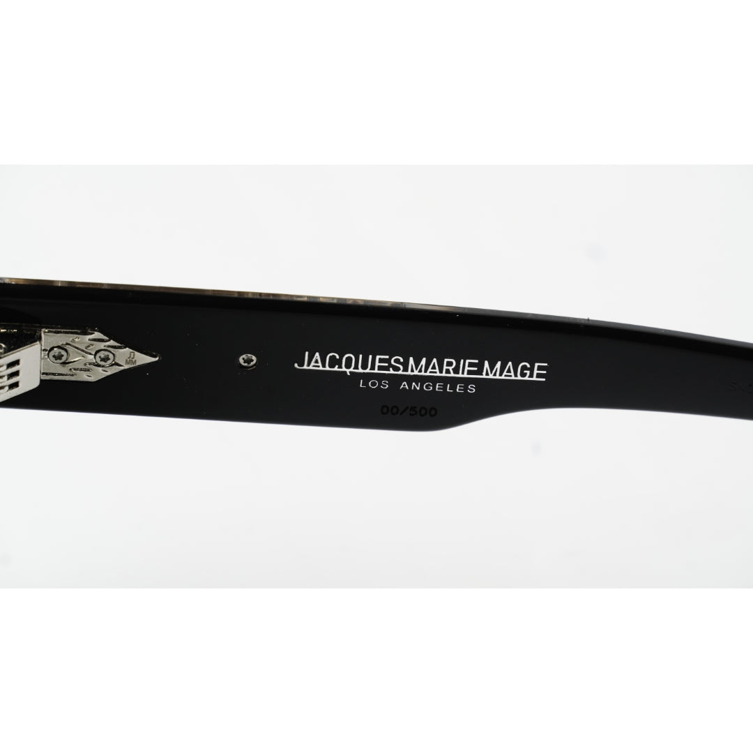 Close-up of a black sunglasses arm with white printed text reading 'JACQUES MARIE MAGE LOS ANGELES' and a small silver logo detail, on a white background.