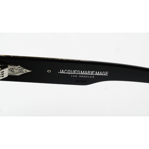 Close-up of a black sunglasses arm with white printed text reading 'JACQUES MARIE MAGE LOS ANGELES' and a small silver logo detail, on a white background.