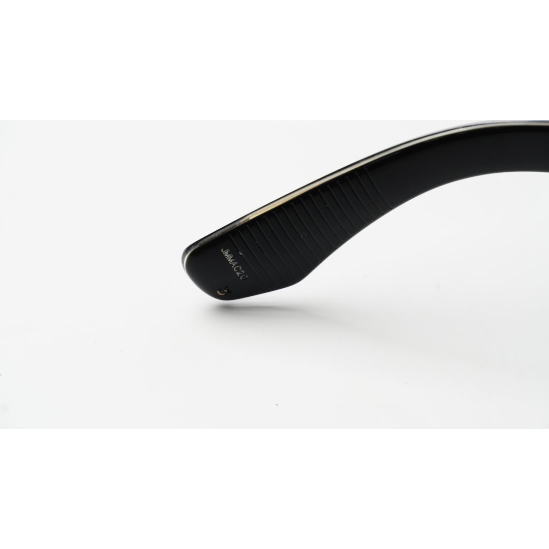 Close-up of the temple arm of black sunglasses with a gold-tone metal core, showing the brand name 'JAPAN IMPORT' on a white background.
