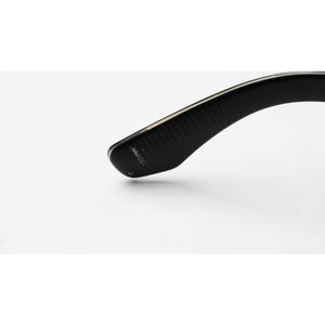 Close-up of the temple arm of black sunglasses with a gold-tone metal core, showing the brand name 'JAPAN IMPORT' on a white background.