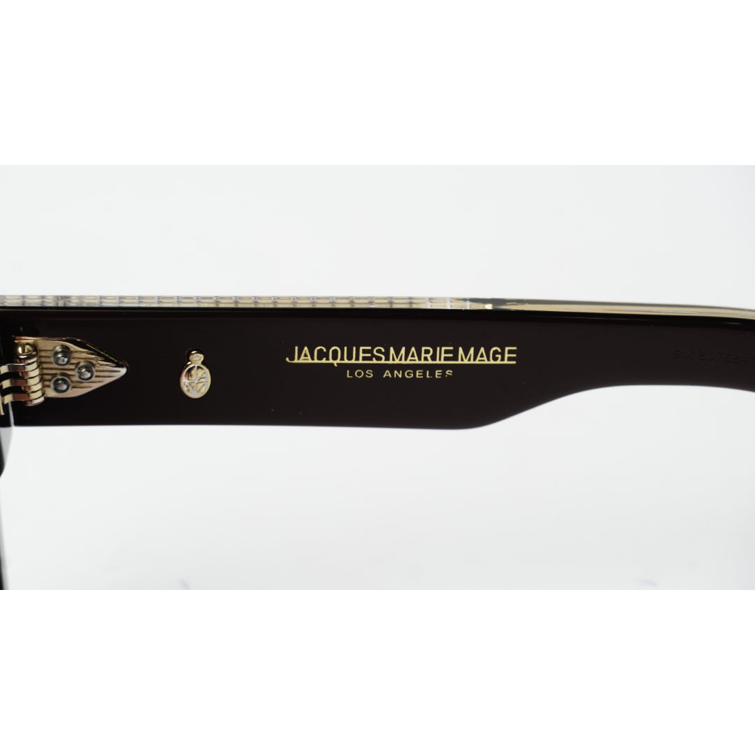 Close-up of a black acetate eyeglass arm featuring gold lettering that reads 'JACQUES MARIE MAGE LOS ANGELES' alongside a small gold crest logo, on a white background.