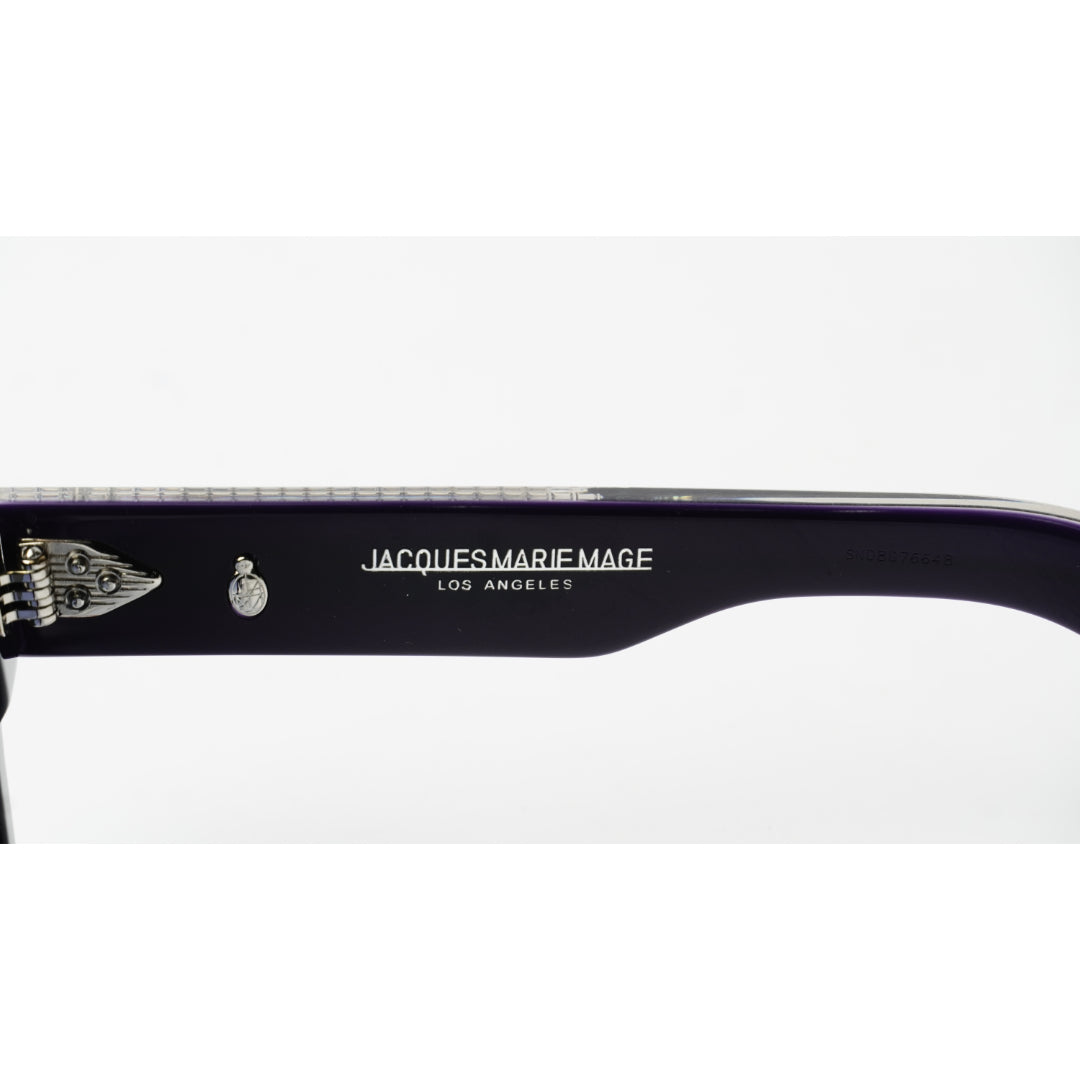 Close-up of a dark purple acetate arm of sunglasses with silver metal hinges, featuring the white printed brand name 'JACQUES MARIE MAGE LOS ANGELES' and a wing emblem.