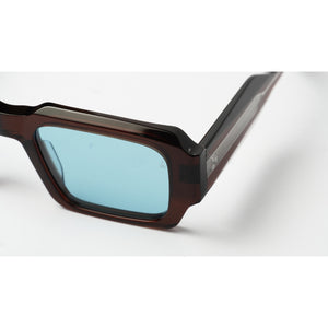 Close-up of a pair of sunglasses with a dark brown translucent acetate frame and light blue tinted lenses, shown on a white background.